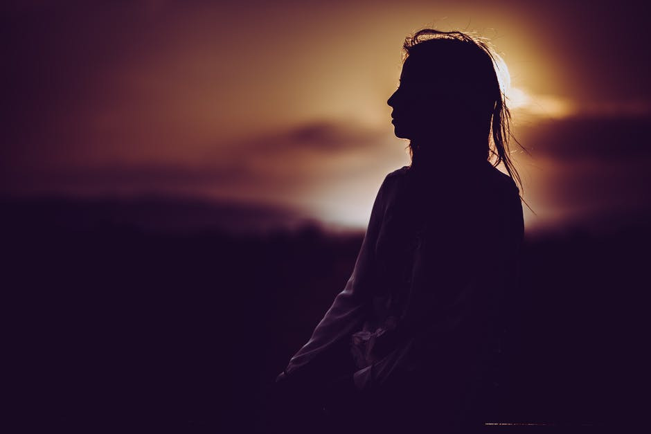 silhouette of woman against sunset